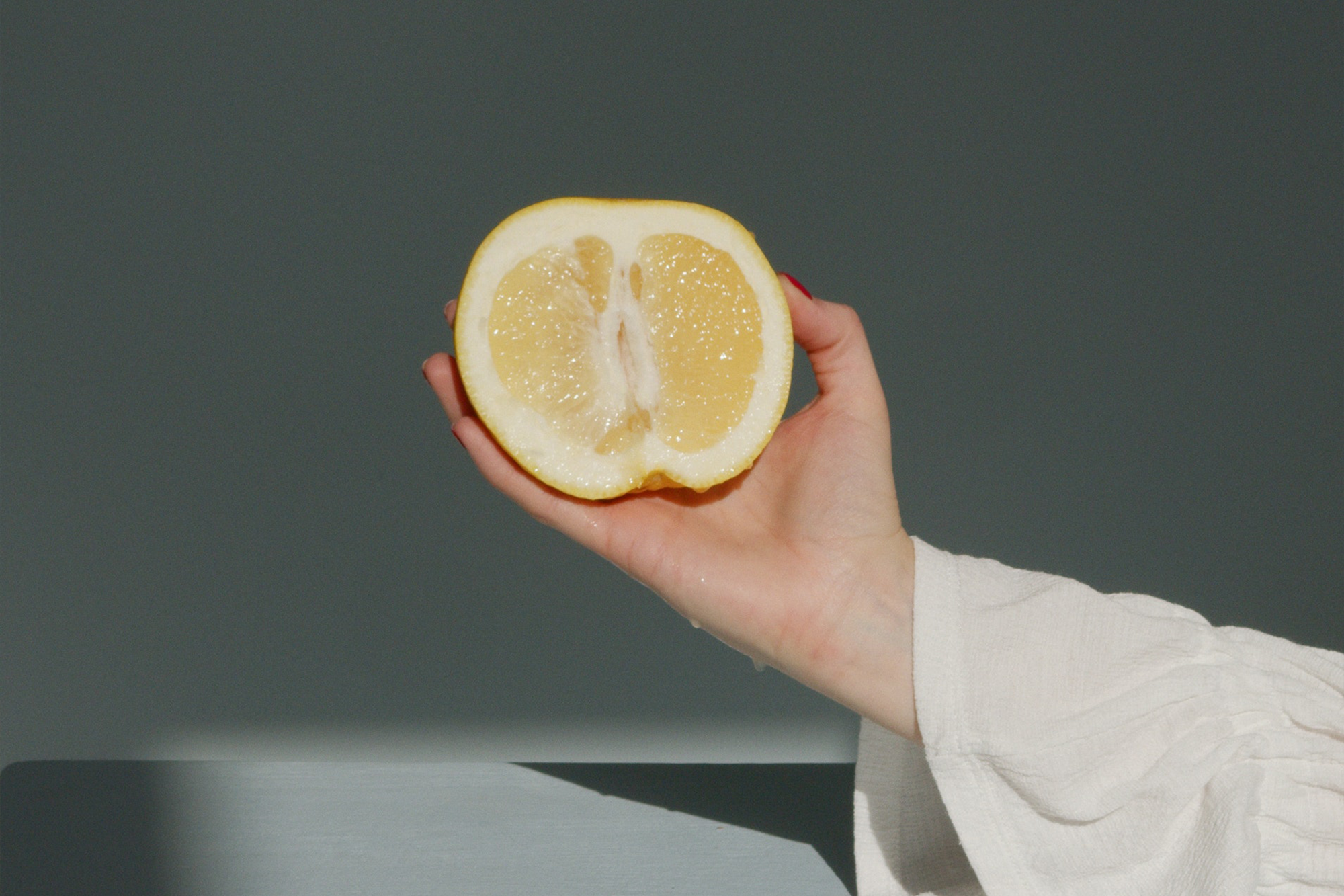 Mano de mujer sujetando limón cortado